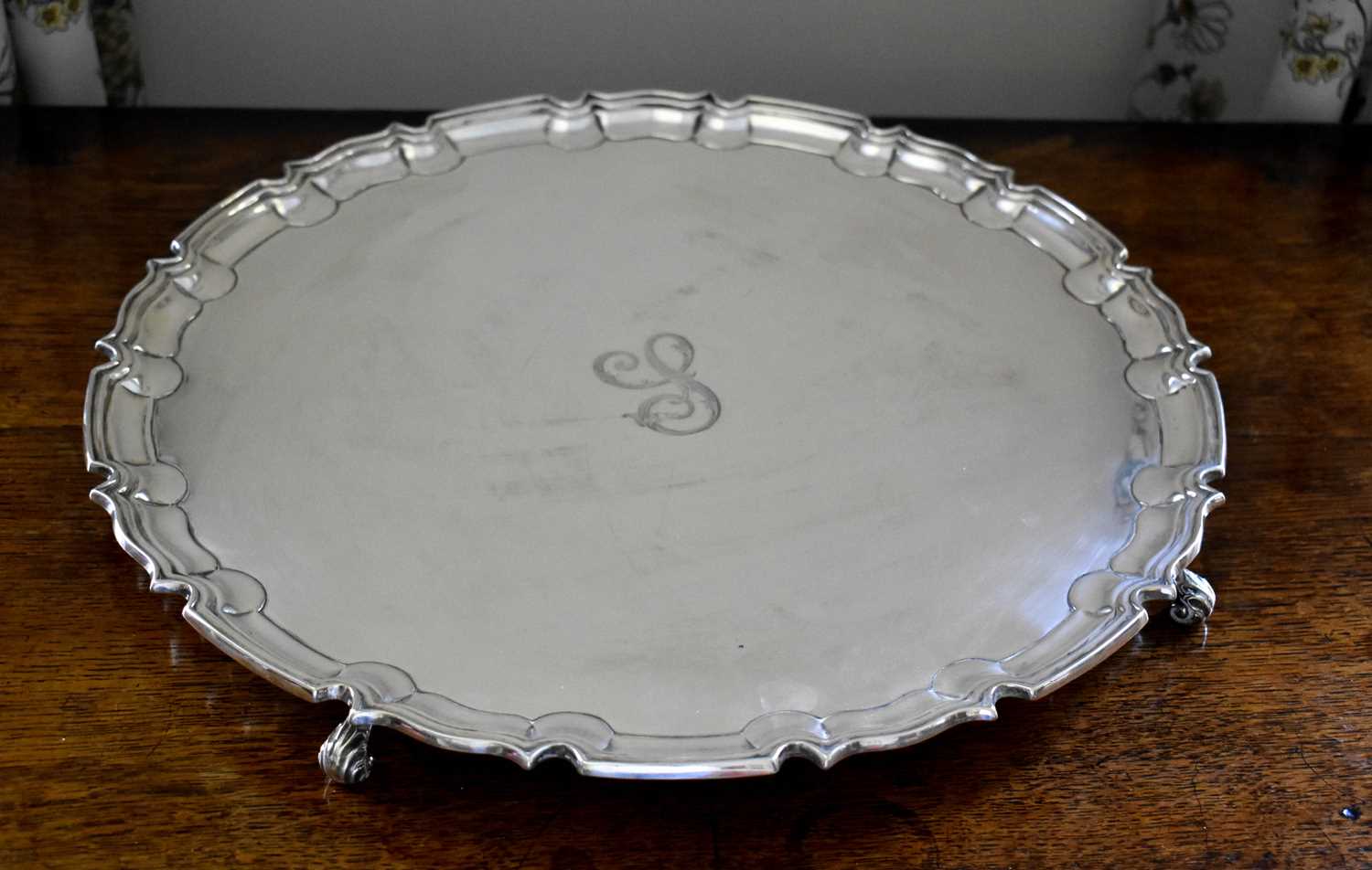A large silver salver, engraved with the initial S, with pie crust moulded edge, and raised on