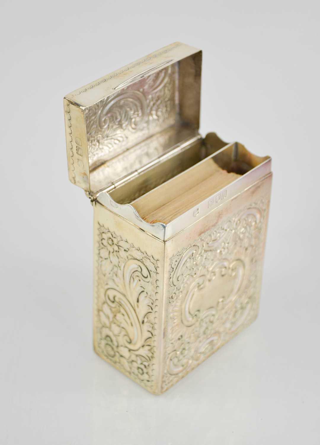 A silver card case, embossed with chased decoration, London 1898, containing a vintage set of cards,