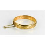 A 9ct gold bangle, with engraved chased design, 19g.