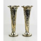 A pair of silver bud vases, embossed with lotus flowers, with wavy rims and weighted bases, engraved