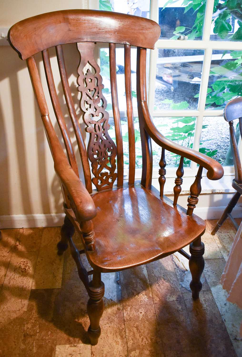 A large 19th century oak kitchen chair, with decoratively carved and pierced splat, the arms