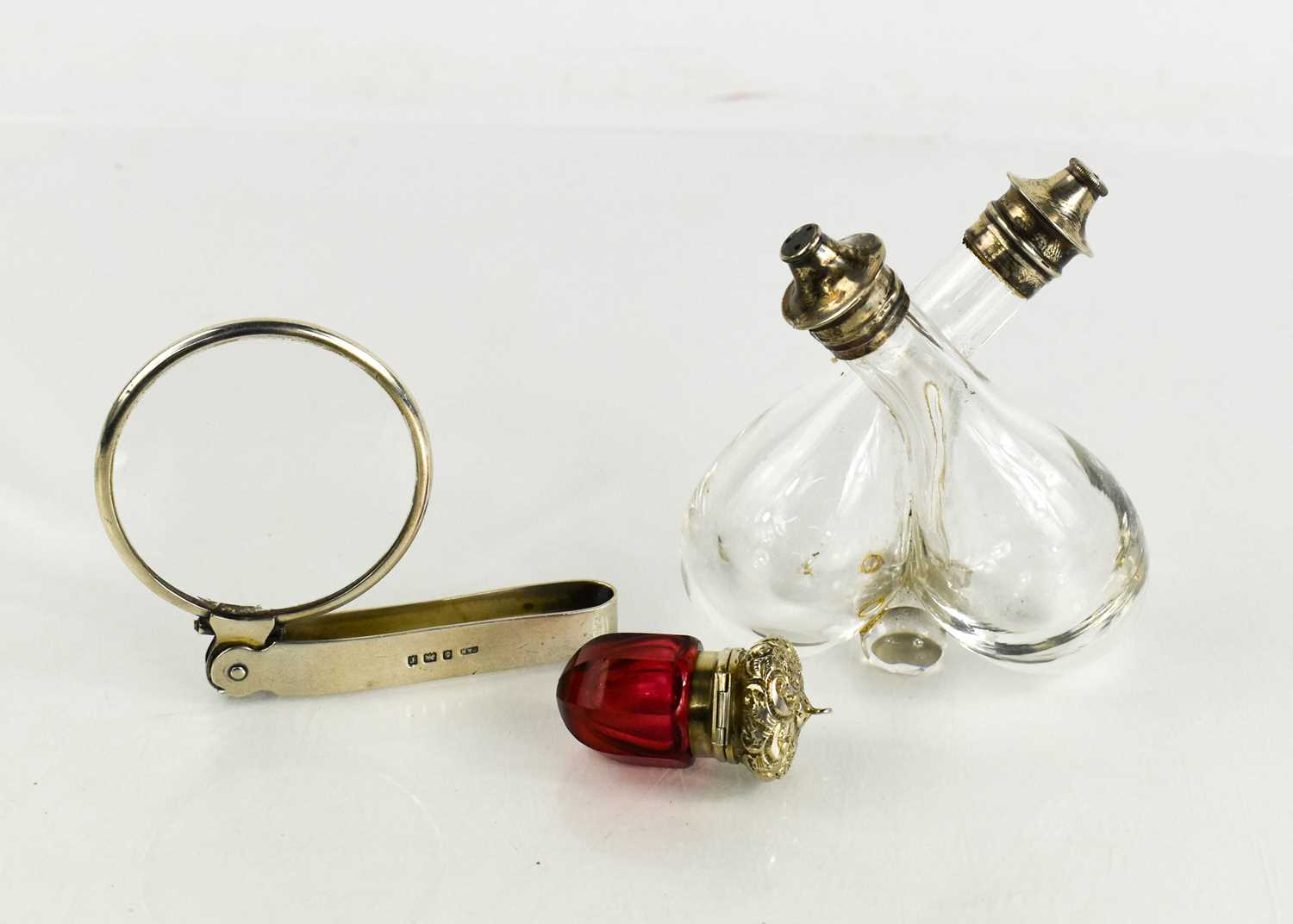 A silver monocle, a silver and cranberry glass vinaigrette, and a twin glass and silver salt and