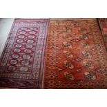 Two Middle Eastern red ground wool rugs with stylised borders, 153cm by 80cm and the other 154cm