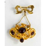 A gold (untested) and ruby coloured cabochon pendant suspended from a 9ct gold bow form brooch, 7.