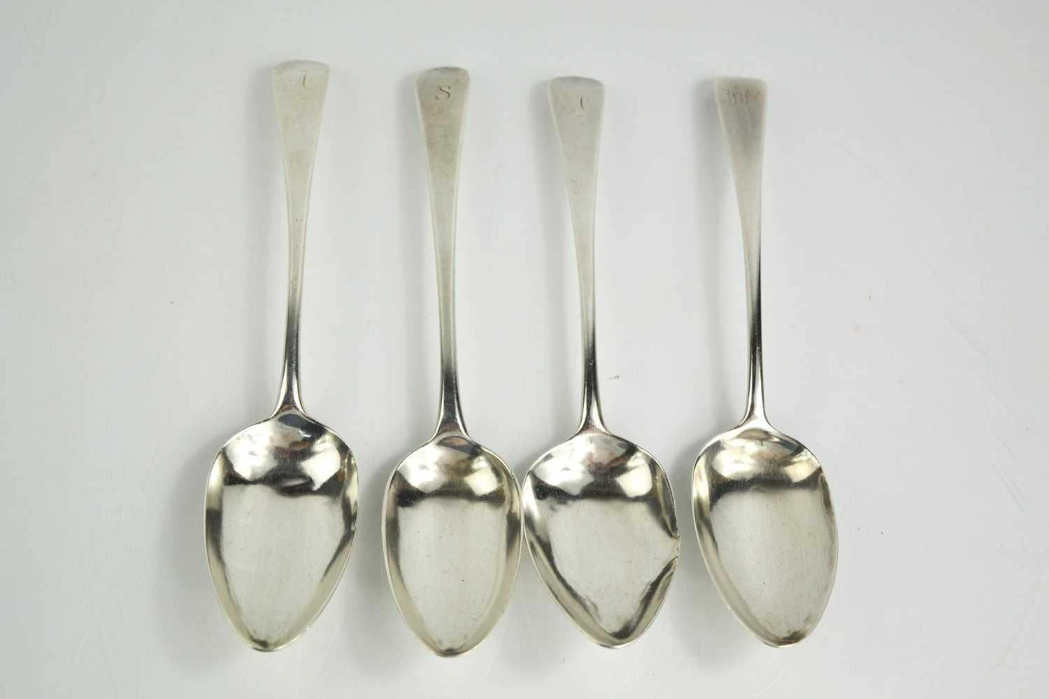 Four silver Georgian serving spoons, each engraved with an initial, 7.8toz.Condition report: One has