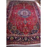 A large Middle Eastern wool rug with magenta ground floral motif to the centre and blue and cream