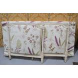 A French style day bed, painted cream and upholstered in a floral linen with cream ground.