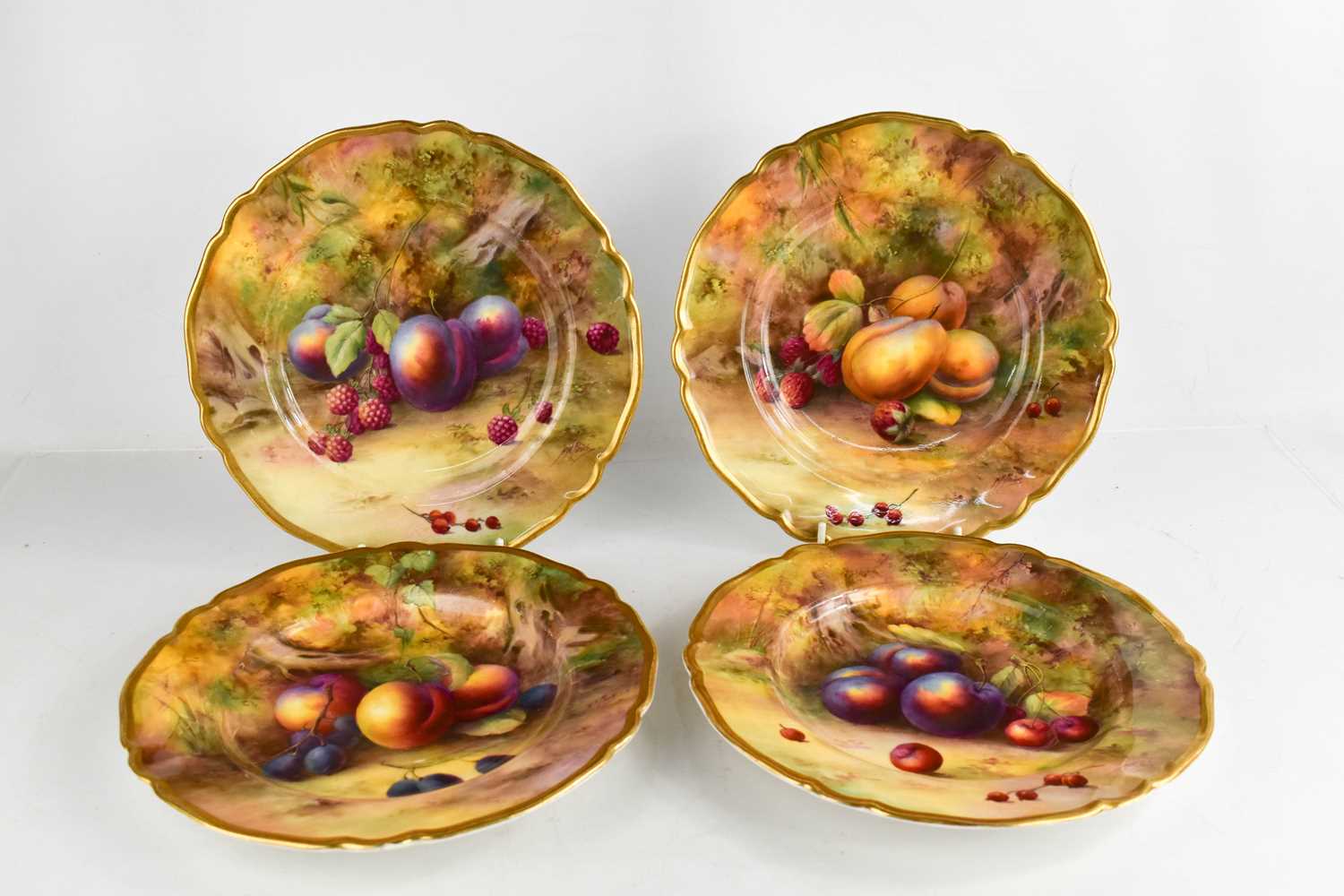 A set of four Royal Worcester plated by Horice Price, painted with fruit on a mossy ground, circa