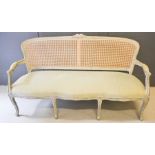A French 19th century style settee, the caned back with floral carved back, shaped arms and