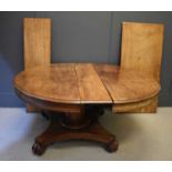 A Victorian mahogany extending pedastal dining table with three extra leaves and raised on a