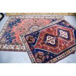 Two Middle Eastern rugs, one wool example with a red and blue ground, and the other with cream