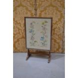 A Victorian needlework tapestry fire screen in an oak frame