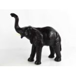 A 20th century leather elephant attributed to Liberty of London, with raised trunk, standing 30cm