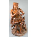 A carved wooden figure of a South American tribesman seated holding a pipe, with a small feline to