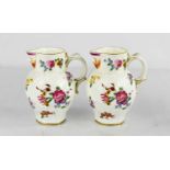 A pair of Royal Worcester leaf moulded jugs with painted roses, face mask spouts and scroll handles,