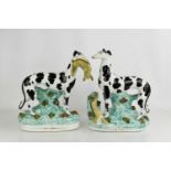 A pair of 19th century Staffordshire greyhounds, with hares, 27cm high.