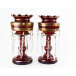 A pair of Victorian ruby glass lustres, with gilt floral decoration, and shaped glass droppers,