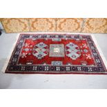 A Middle Eastern rug with a red ground, blue stylised motifs, 93 by 155cm.