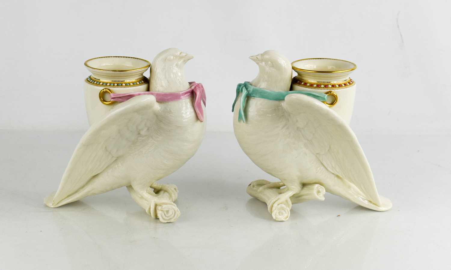 A pair of Royal Worcester porcelain spill vases, modelled as doves perched on a branch with urn to