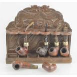 An Oriental dragon design wooden smoking pipe rack together with a quantity of pipes to include K&