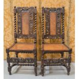 A pair of Carolean walnut hall chairs carved with scroll work and the top rail bearing crowns
