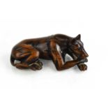 A Japanese wooden netsuke, likely Meiji period, carved in the form of a dog, lying prone, his paws
