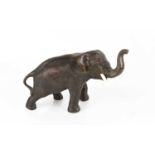 A 19th century bronze elephant with ivory tusks, bearing Chinese calligraphy marks to the belly,