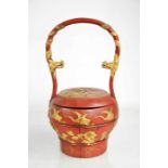 A Chinese red lacquered wedding handbag circa 1900, with carved and gilded decoration, the handle