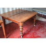 A large Victorian mahogany dining table with three extra leaves, the boldly turned legs raised on