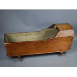 An antique dolls cradle, in stained pine, raised on rockers, 55cm long.