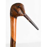 A treen walking cane, carved in the form of a bird head, painted with detail and inset with glass