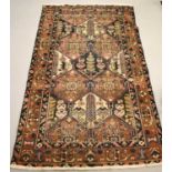 A Middle Eastern woollen rug with dark blue ground and depicting stylised foliage and bird to the