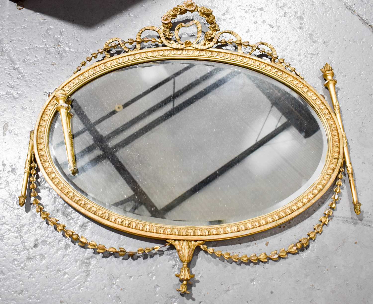 A 19th century oval giltwood mirror, with two pillars holding flames to either side, harebell and