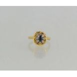 An 18ct gold, sapphire and diamond ring of raised flowerhead form, the central oval sapphire of