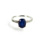 A 9ct white gold, sapphire and diamond ring, the oval cut sapphire in a four claw setting flanked by