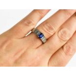 A white gold, sapphire and diamond ring, the emerald-cut sapphire, in a four claw setting, between