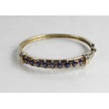 A Q.V.C. tanzanite and silver bangle of nine princess cut stones 20.17g, internal dimensions 61.5 by