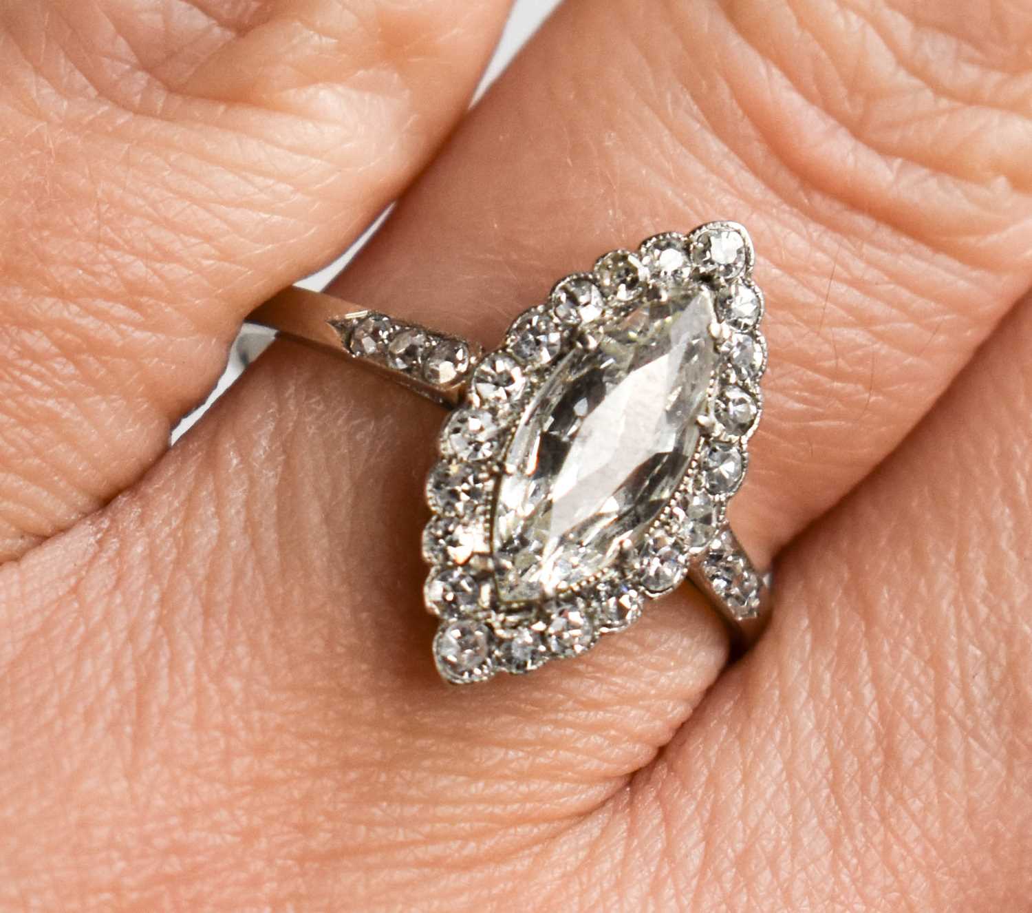 A platinum and diamond ring, the central marquise cut diamond bordered by diamonds, and to the
