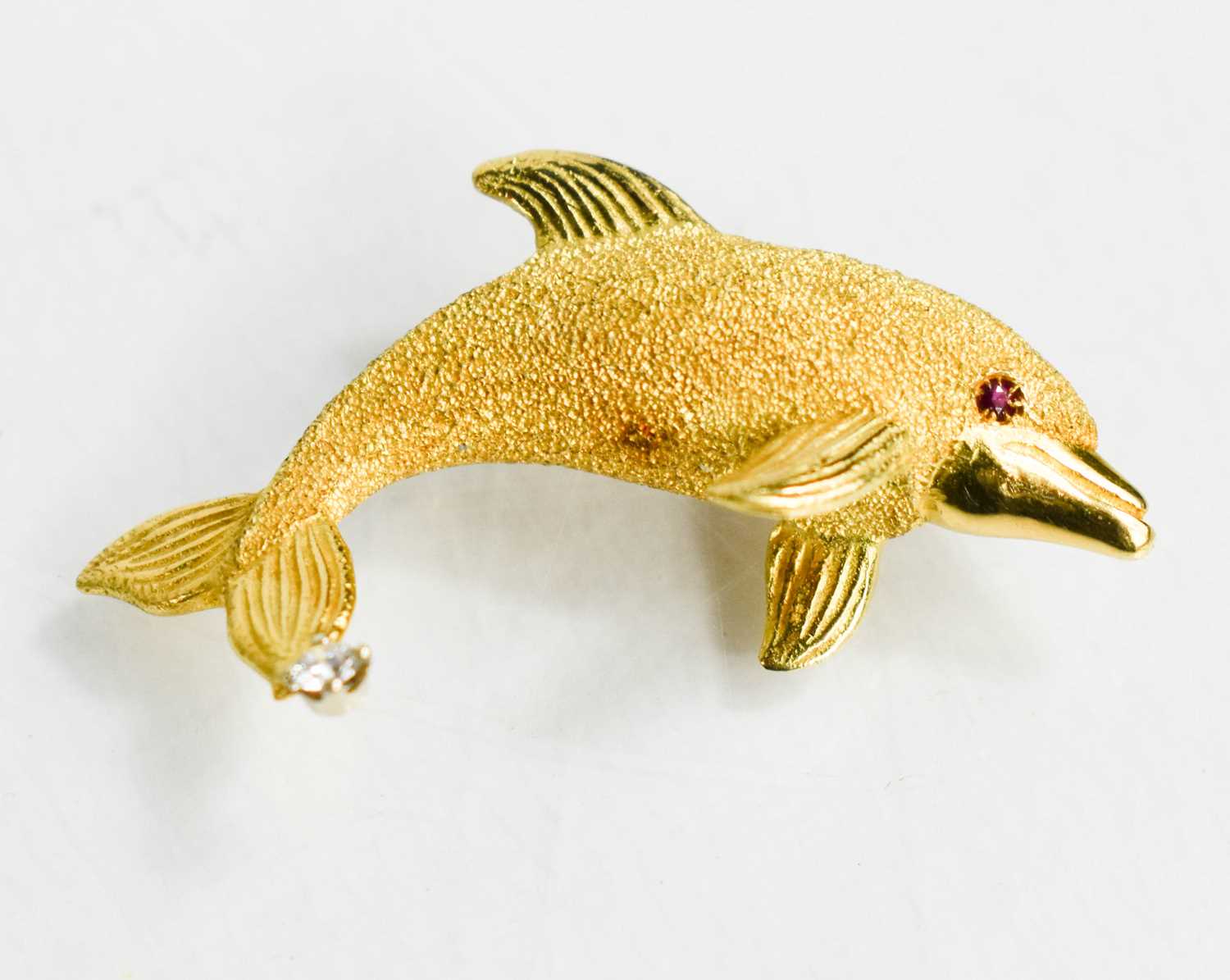 An 18ct gold, ruby and diamond brooch, with a textured body, ruby eye and diamond to the tail, 3.7g.