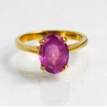 An 18ct gold pink sapphire solitaire dress ring, the oval cut stone of approximately 10 by 7.6mm,