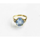 A 9ct gold, blue topaz and diamond ring, the oval cut topaz flanked by three diamonds set to the