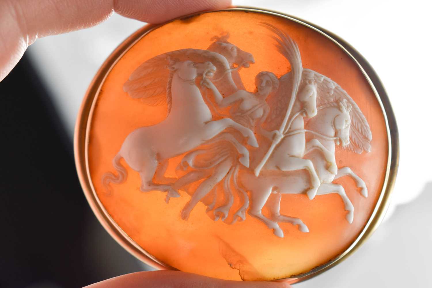 A 19th century cameo brooch, carved with a winged angel and horses, set in a gold (untested,