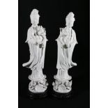 A pair of blanc de chine figures of Quan Yin holding a lotus flower and standing on a lotus flower