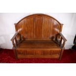 Antique oak settle with high panel back above hinged bench seat, raised on bun supports, 126cm