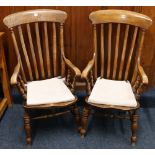 Pair of antique elm armchairs with recurved spar back, scroll arms, saddled seats raised on turned