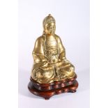 Early 20th century Chinese brass Buddha, seated in padmasana, on a carved wooden stand, 24.5cm