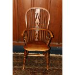Antique elm Windsor style arm chair with spindle and splat back rest, saddled seat and raised on