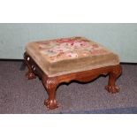 Victorian mahogany upholstered footstool, the square floral top raised on ball and claw supports.
