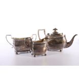 George III silver three piece tea set of boat shape with engraved band of foliage designs by maker