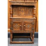 Antique craved oak court cupboard of small proportions having central door above two further panel
